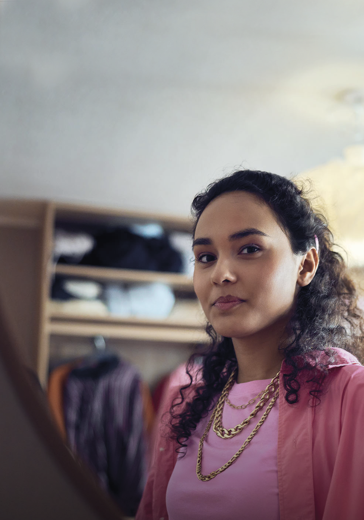 A woman is standing in front of a mirror, wearing a pink shirt. AI generated content