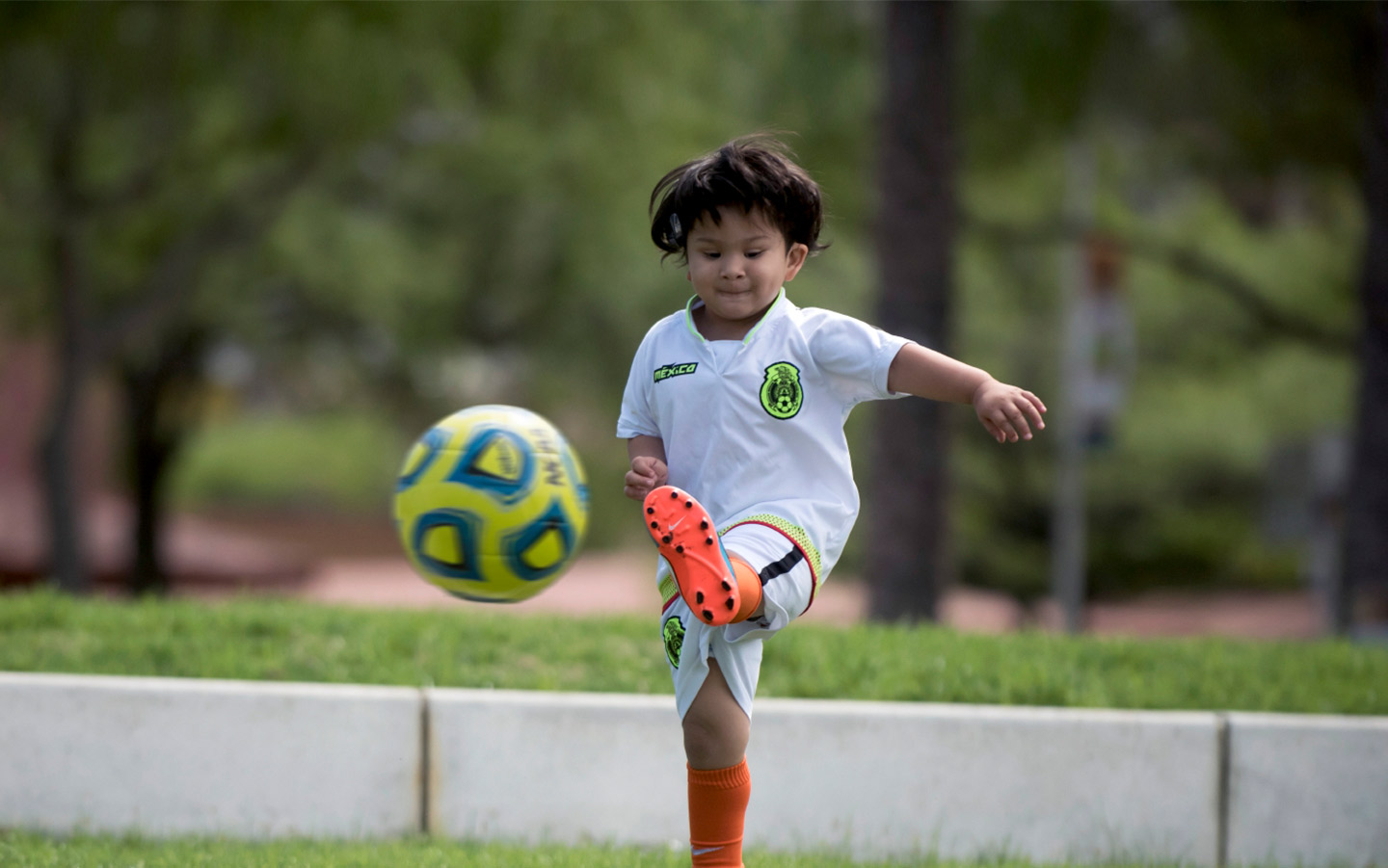 Criança jogando futebol com processador de som Baha