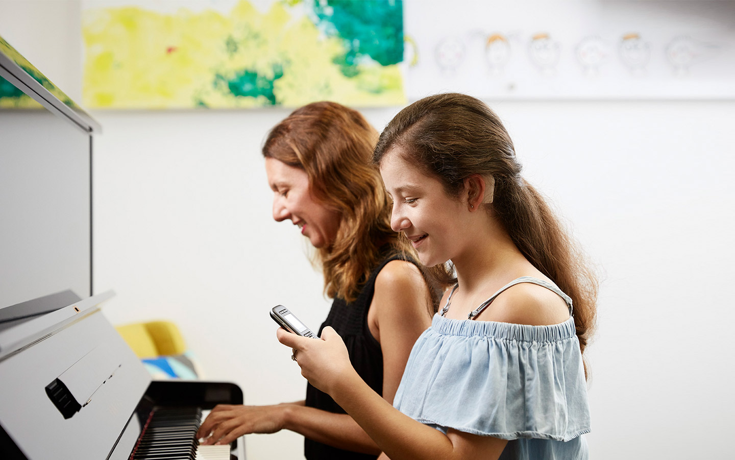 Uma adolescente usa microfone enquanto a mãe toca piano