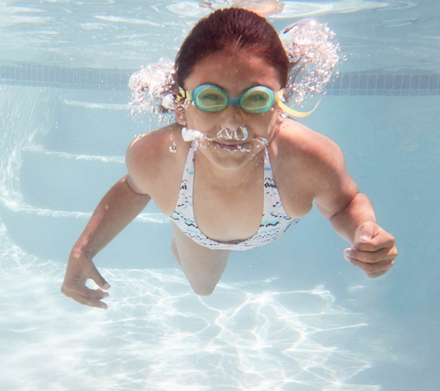 Criança nadando debaixo da água com um implante da Cochlear