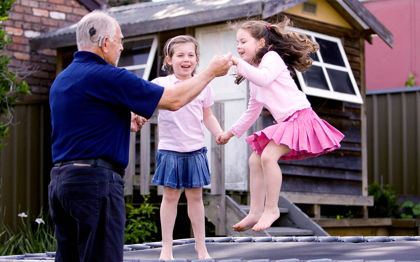 Grandpa playing trampoline with 2 granddaughters